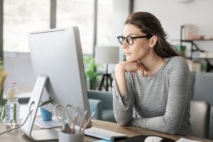 Professional woman sitting at desk and connecting with her computer, she is working from home